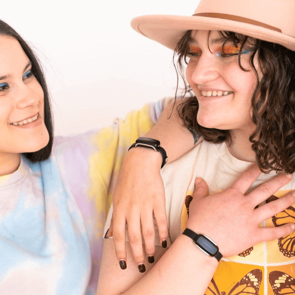 Two friends wearing Bond Touch Bracelets, hugging and smiling 